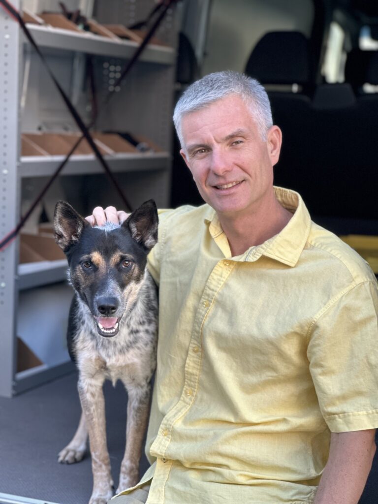 Silver Fox Alex Tkachenko and his dog sitting in the back of a work truck